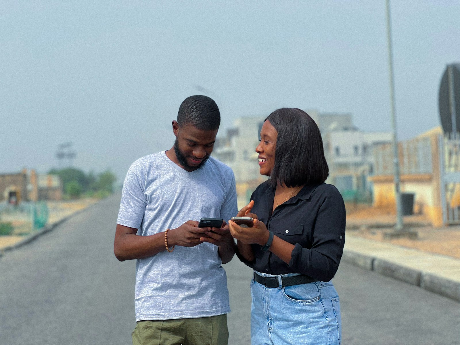 Two young professionals talking through something on a phone, outdoors in a Nigerian city